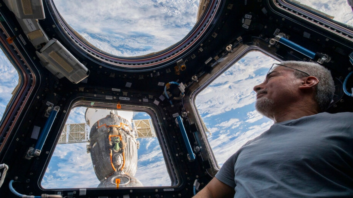 In this photo provided by NASA, U.S. astronaut and Expedition 66 Flight Engineer Mark Vande Hei peers at the Earth below from inside the seven-windowed cupola, the International Space Station's window to the world on Feb. 4, 2022.  