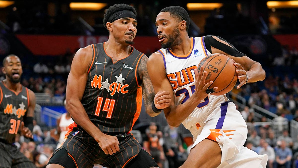 Phoenix Suns' Mikal Bridges, right, drives past Orlando Magic's Gary Harris (14) during the second half of an NBA basketball game, Tuesday, March 8, 2022, in Orlando, Fla.