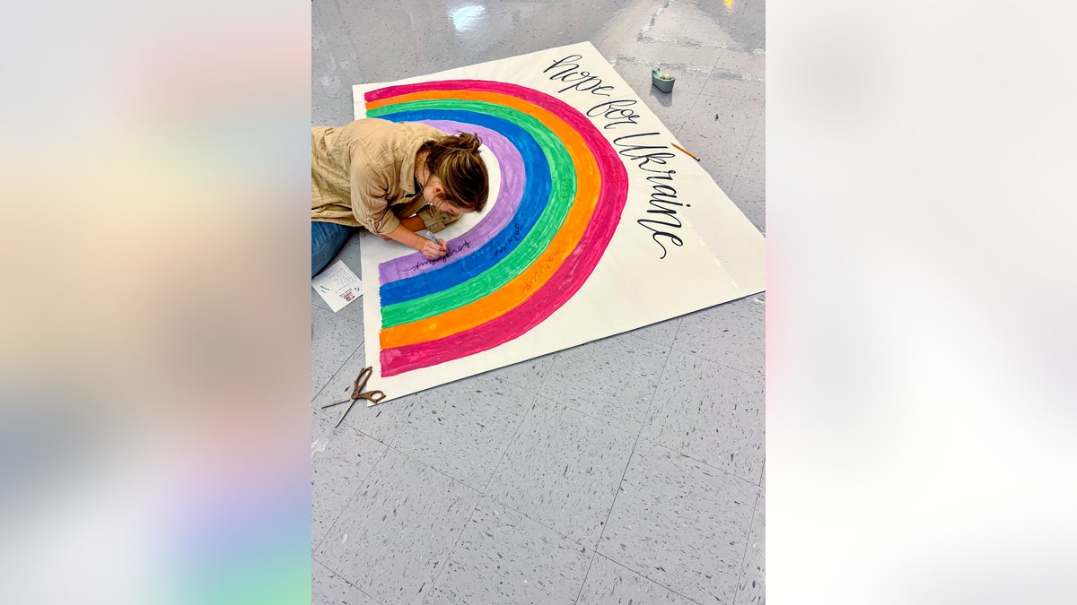 A teacher is shown creating rainbow art to express support for Ukraine native Lana Gazhenko, head custodian at Oak Hill Elementary School.