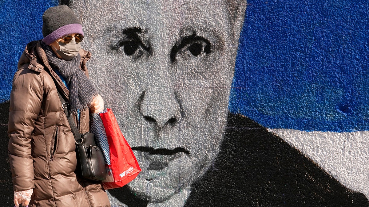 A woman passes by a mural depicting the Russian President Vladimir Putin in Belgrade, Serbia, Saturday, March 12, 2022. (AP Photo/Darko Vojinovic)