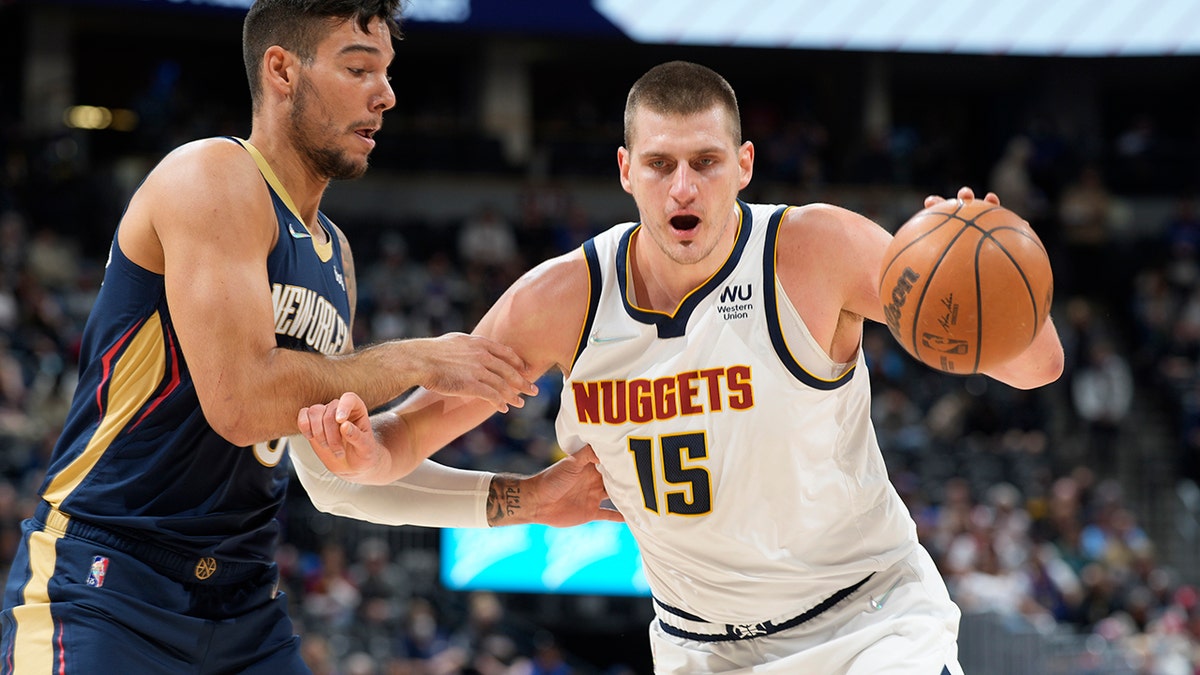 Denver Nuggets center Nikola Jokic, right, drives the lane to the rim as New Orleans Pelicans center Willy Hernangomez defends in the first half of an NBA basketball game Sunday, March 6, 2022, in Denver.