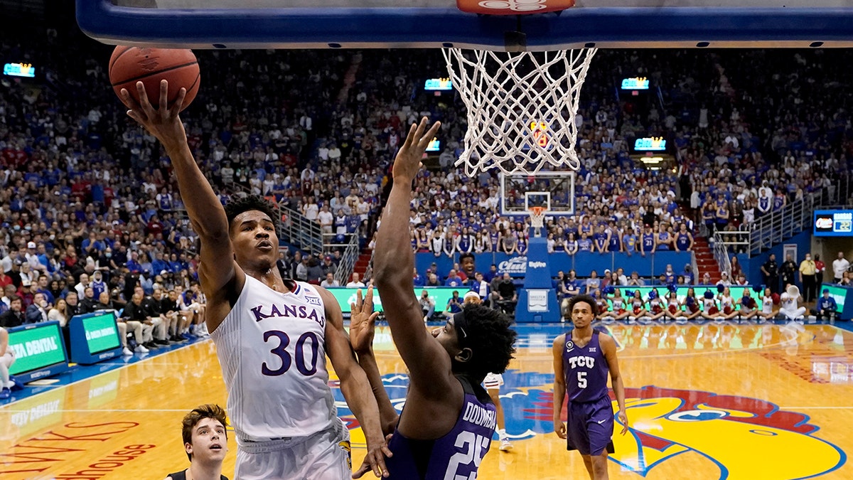 Kansas guard Ochai Agbaji (30) gets past TCU center Souleymane Doumbia (25) to put up a shot during the first half of an NCAA college basketball game Thursday, March 3, 2022, in Lawrence, Kan.