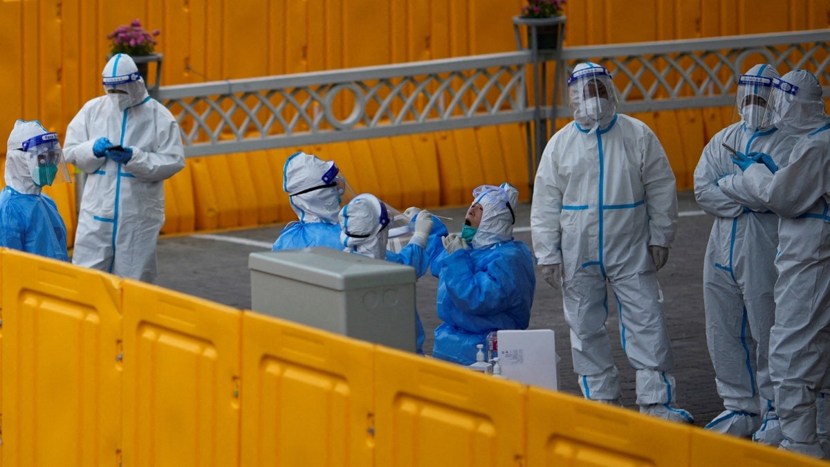 Policemen and staff workers get tested for the coronavirus disease (COVID-19) at a makeshift nucleic acid testing centre inside barriers of an area under lockdown amid the coronavirus disease (COVID-19) pandemic, in Shanghai, China March 24, 2022.