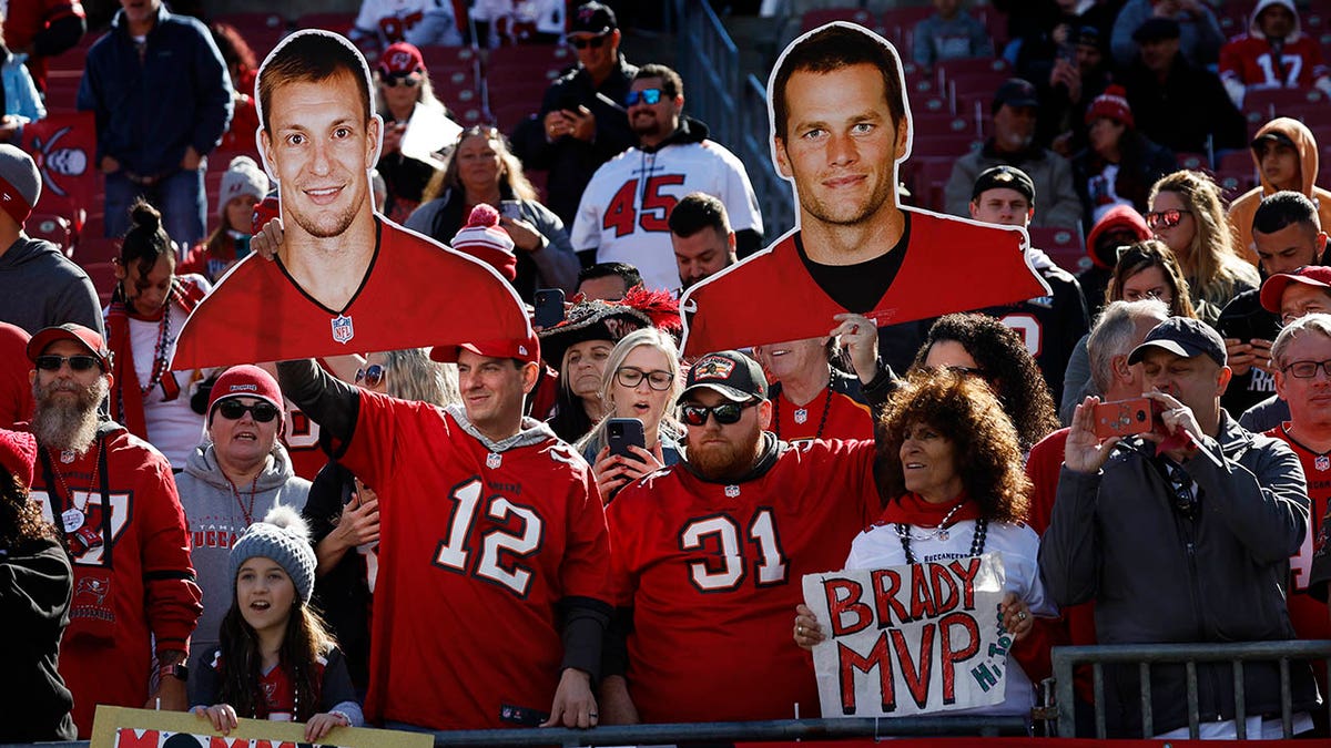 Tampa Bay Buccaneers fans hold up cardboard cutouts of Tampa Bay Buccaneers tight end Rob Gronkowski (87) and quarterback Tom Brady (12) during the game against the Rams in the NFC Divisional game at Raymond James Stadium on January 23, 2022 in Tampa Bay, Florida. Brady announced today that he is retiring after 22 years in the NFL