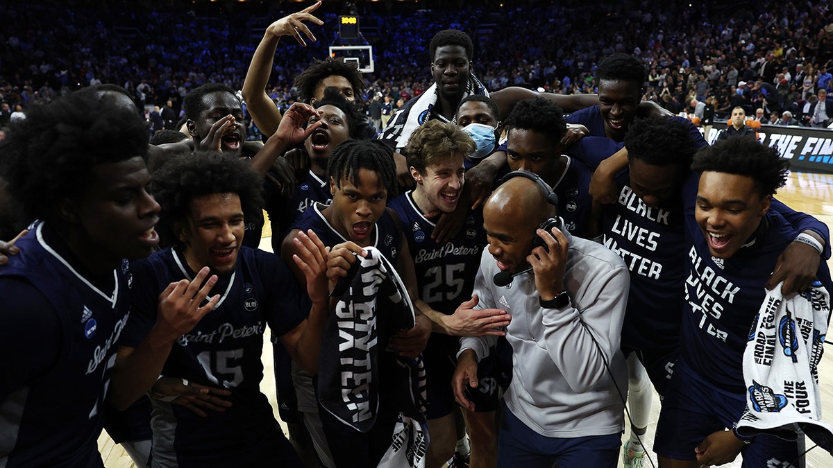 St. Peter's Peacocks players celebrate with head coach Shaheen Holloway after defeating the Purdue Boilermakers 67-64 in the Sweet Sixteen round game of the 2022 NCAA Men's Basketball Tournament at Wells Fargo Center on March 25, 2022 in Philadelphia, Pennsylvania.