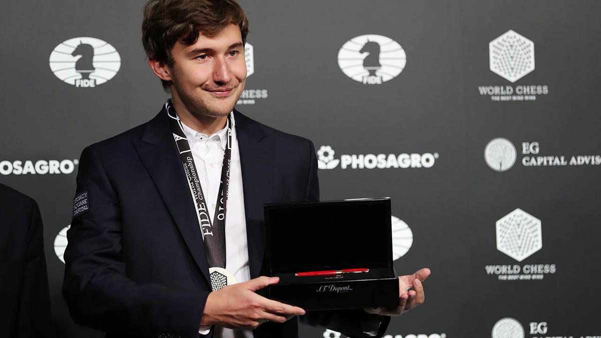 Sergey Karjakin of Russia wears a medal and holds a commemorative pen after losing to Magnus Carlsen of Norway at the 2016 World Chess Championship match in New York, Nov. 30, 2016.