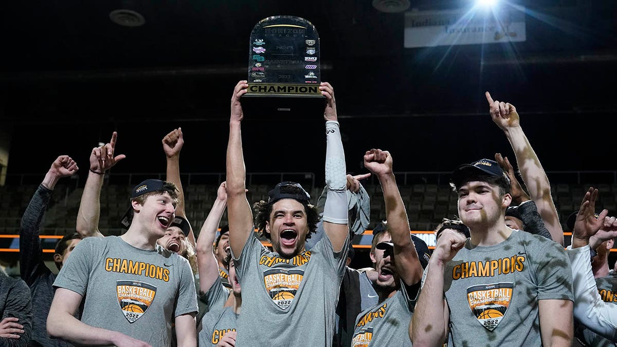 Wright State's Tanner Holden holds up the trophy and celebrates with teammates following an NCAA college basketball game against Northern Kentucky for the Horizon League men's tournament championship Tuesday, March 8, 2022, in Indianapolis. Wright State won 72-71.