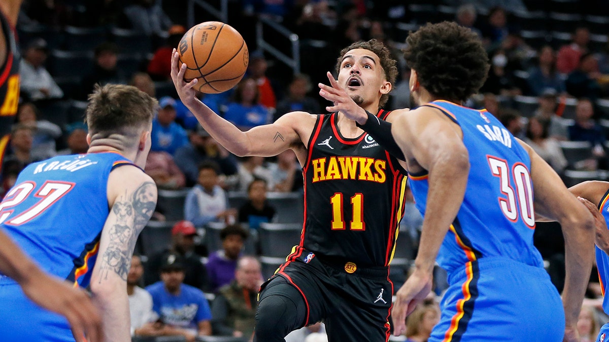 Atlanta Hawks guard Trae Young (11) prepares to shoot as Oklahoma City Thunder guard Vit Krejci, left, and center Olivier Sarr (30) defend during the first half of an NBA basketball game Wednesday, March 30, 2022, in Oklahoma City.