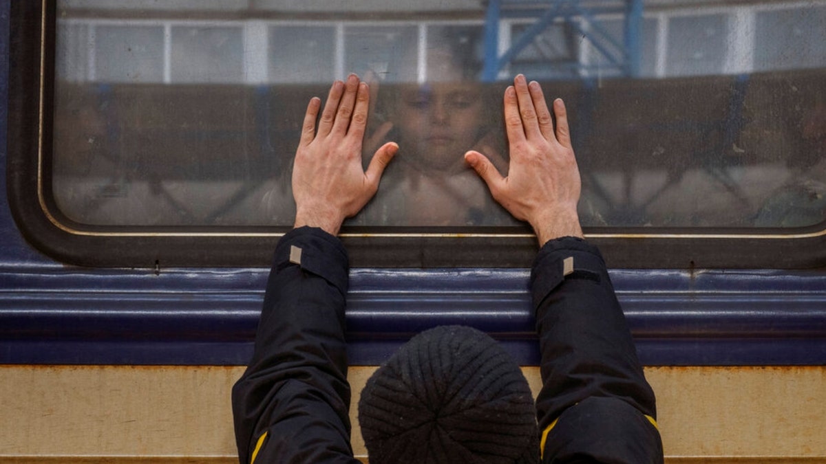 Aleksander, 41, presses his palms against the window as he says goodbye to his daughter Anna, 5, on a train to Lviv at the Kyiv station, Ukraine, Friday, March 4. 2022. Aleksander has to stay behind to fight in the war while his family leaves the country to seek refuge in a neighboring country.