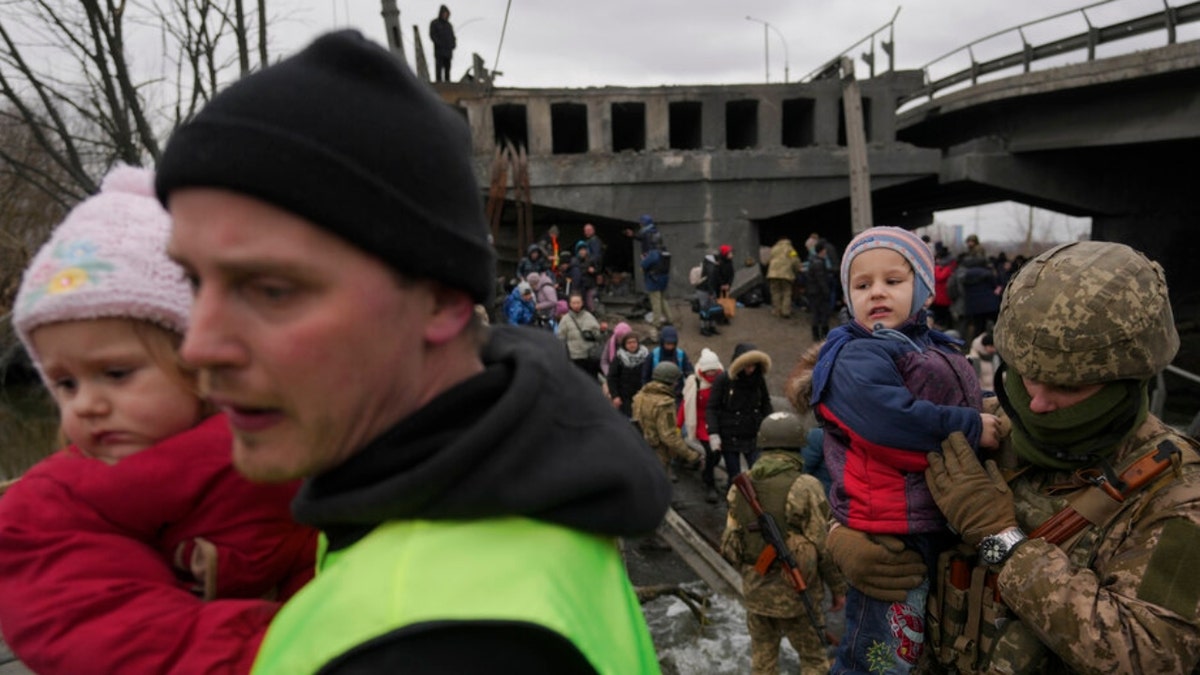 A Ukrainian serviceman holds a baby crossing the Irpin river on an improvised path under a bridge that was destroyed by a Russian airstrike, while assisting people fleeing the town of Irpin, Ukraine, Saturday, March 5, 2022. What looked like a breakthrough cease-fire to evacuate residents from two cities in Ukraine quickly fell apart Saturday as Ukrainian officials said shelling had halted the work to remove civilians hours after Russia announced the deal.