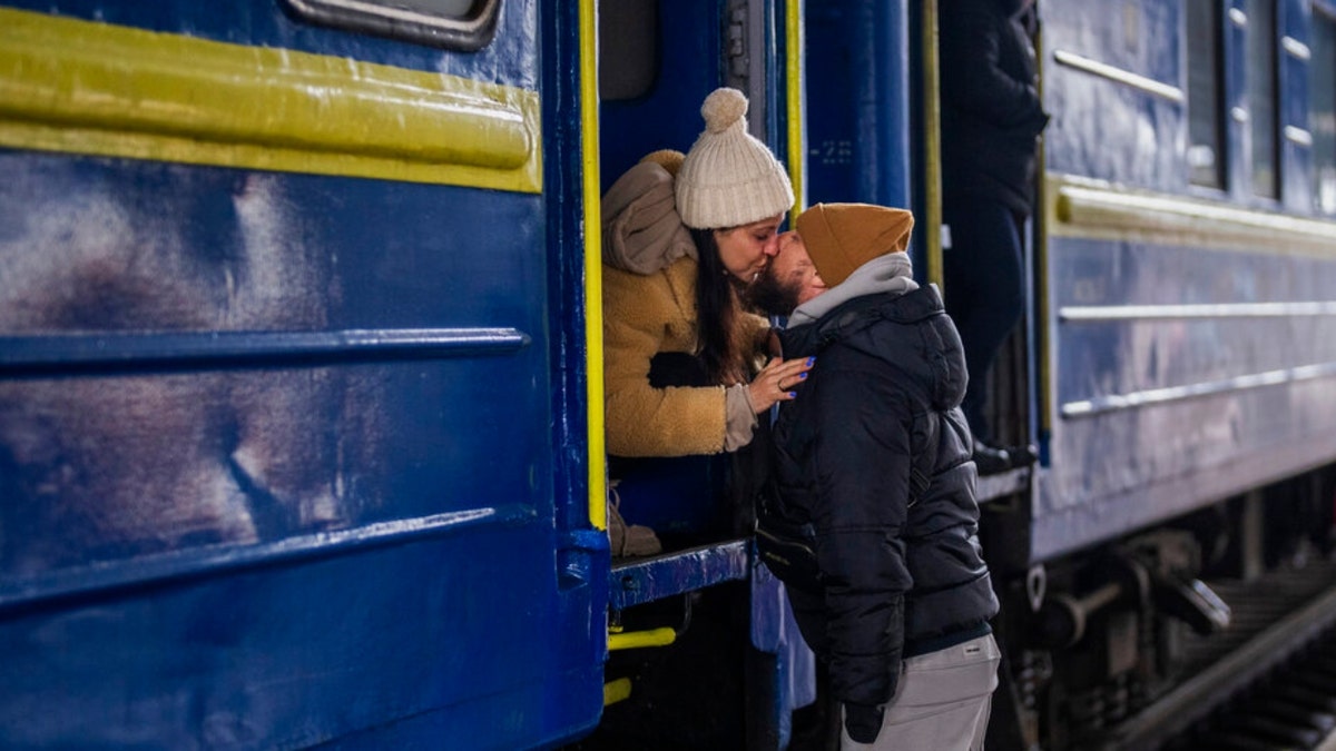 Stanislav, 40, kisses his wife Anna, 35, on a train to Lviv as they say goodbye at the Kyiv station, Ukraine, Thursday, March 3. 2022. Stanislav is staying to fight while his family is leaving the country to seek refuge in a neighboring country.