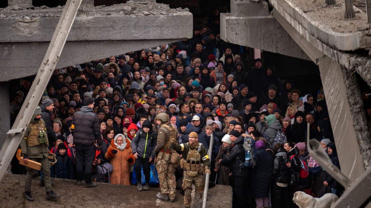 Ukrainians crowd under a destroyed bridge as they try to flee crossing the Irpin river in the outskirts of Kyiv, Ukraine, Saturday, March 5, 2022. (AP Photo/Emilio Morenatti) 