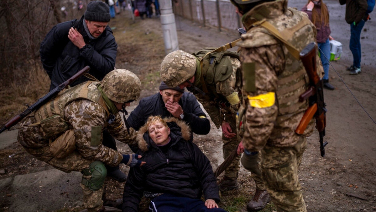 A semi-conscious woman is attended to by Ukrainian soldiers after crossing the Irpin river as fleeing the city in the outskirts of Kyiv, Ukraine, Saturday, March 5, 2022.