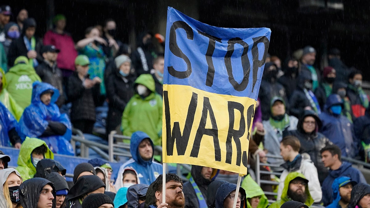 A Seattle Sounders supporter holds a sign that reads "Stop Wars" during a moment of silence for victims of the war in Ukraine, before the start of an MLS soccer match between the Sounders and Nashville SC, Sunday, Feb. 27, 2022, in Seattle.