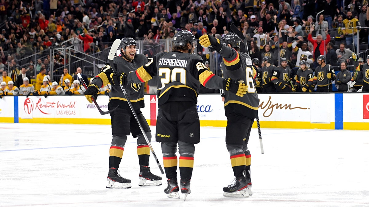 Vegas Golden Knights defenseman Shea Theodore (27), center Chandler Stephenson (20) and right wing Evgenii Dadonov (63) celebrate Dadonov's goal against the Nashville Predators during the second period of an NHL hockey game Thursday, March 24, 2022, in Las Vegas.