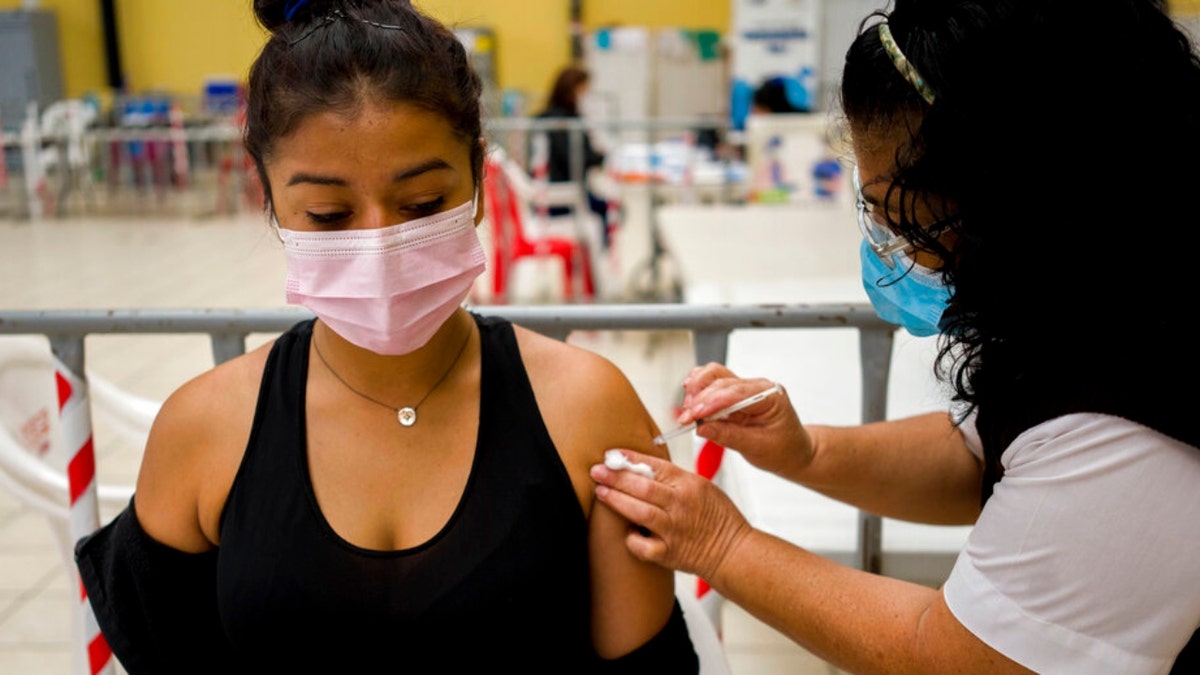 A healthcare worker administers a booster dose of a COVID 19 vaccine at a temporary vaccine center in Guatemala City, Tuesday , March 1, 2022. Health authorities in Guatemala say over a million doses of the Russian Sputnik coronavirus vaccine have expired, because nobody wanted to take the shot. (AP Photo/Moises Castillo)