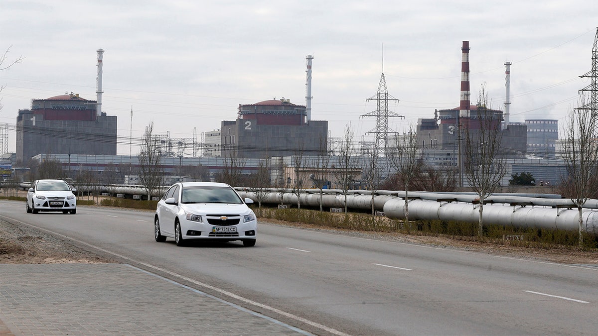 white cars drive by three power centers at Zaporizhzhya nuclear plant Enerhodar