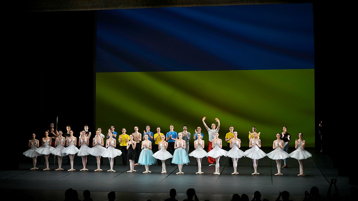Ukrainian dancers of the Kyiv City Ballet company acknowledge applause in front of Ukrainian flag projected onto a screen at the end of a performance, at the Theatre de Chatelet, in Paris, Tuesday, March 8, 2022. 