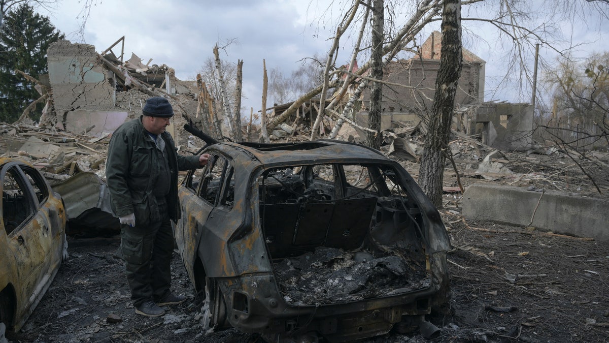A man stands next to a burnt car near a cultural and community centre, which locals said was destroyed by recent shelling, as Russia's invasion of Ukraine continues, in the settlement of Byshiv in the Kyiv region, Ukraine on March 4, 2022.