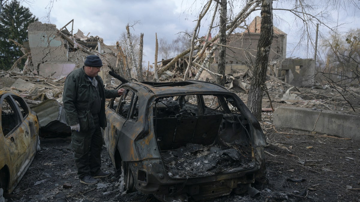 A man stands next to a burnt car near a cultural and community centre, which locals said was destroyed by recent shelling, as Russia's invasion of Ukraine continues, in the settlement of Byshiv in the Kyiv region, Ukraine on March 4, 2022.