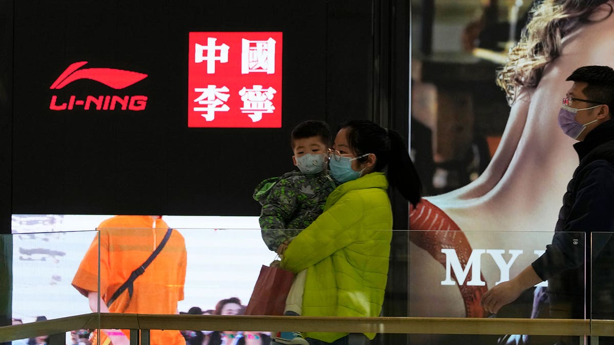 Visitors to a mall walk past signs of Chinese sports brand Li Ning on Wednesday, March 16, 2022, in Beijing. 