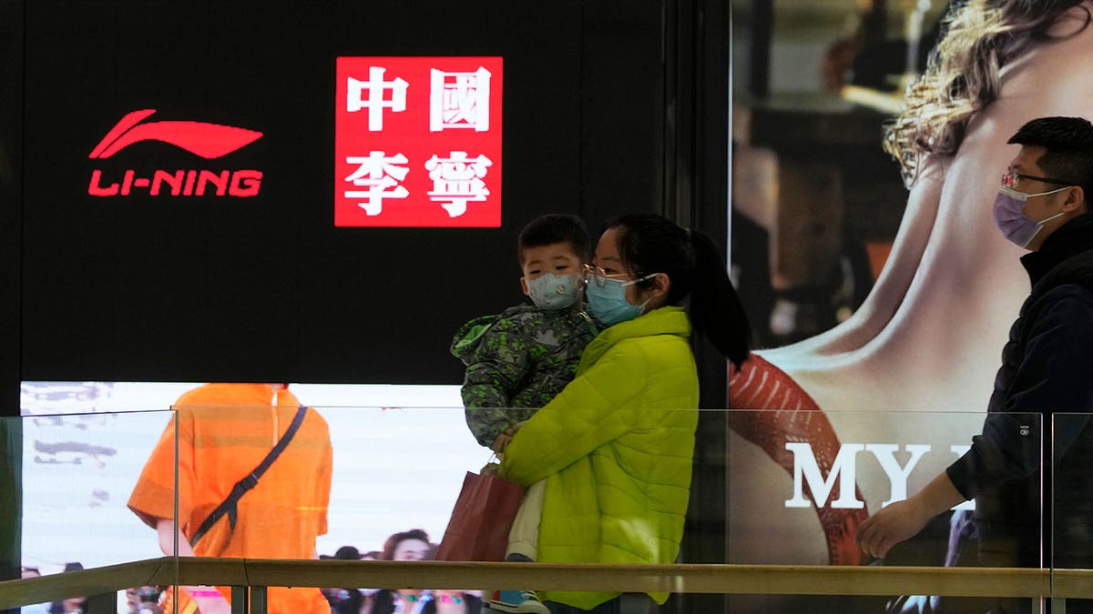 Visitors to a mall walk past signs of Chinese sports brand Li Ning on Wednesday, March 16, 2022, in Beijing.?