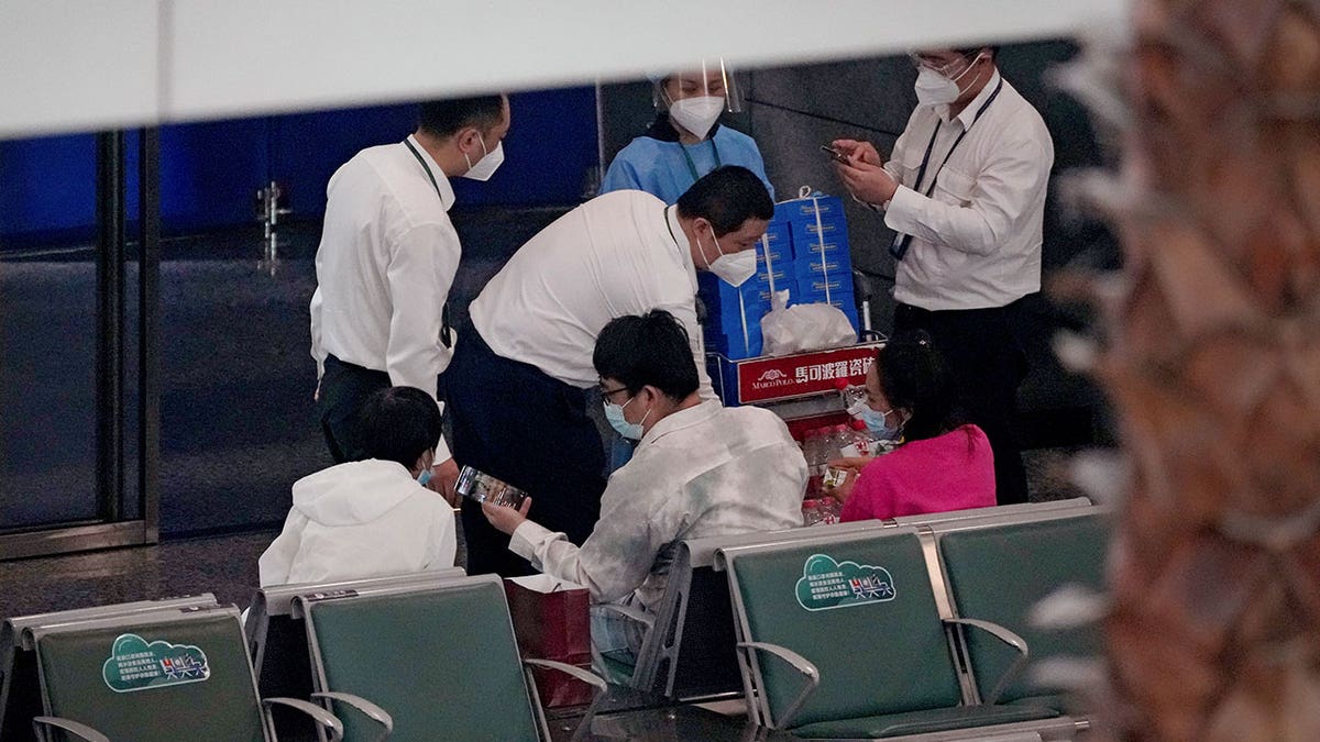 Workers provide beverages to people in a cordoned off area for relatives of the victims aboard China Eastern's flight MU5735