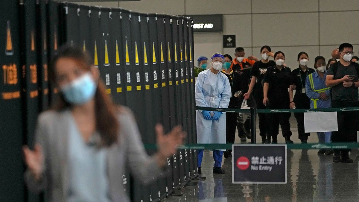 Workers and security personnel talk with a journalist reporting near a cordoned off area for the relatives of victims aboard China Eastern's flight MU5735