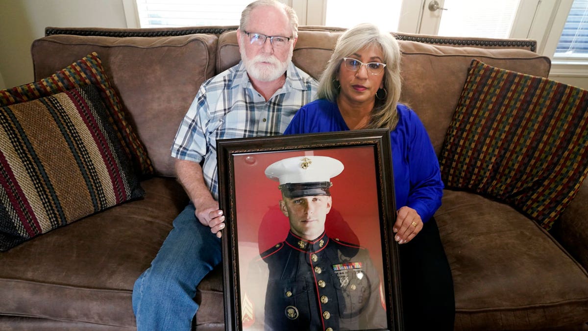 Joey and Paula Reed pose for a photo with a portrait of their son Marine veteran and Russian prisoner Trevor Reed at their home in Fort Worth, Texas, Feb. 15, 2022. 