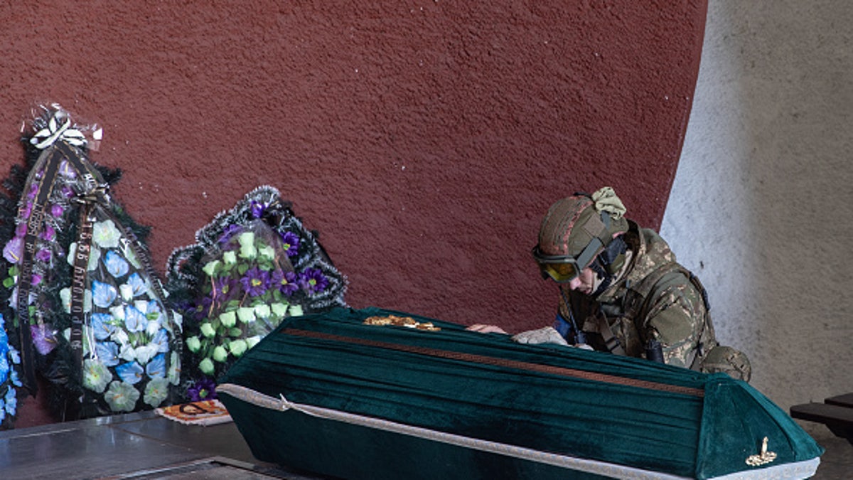 Ukrainian soldier Yaroslav prays over the coffin of his father, a member of the Ukrainian military who was killed in recent fighting on the outskirts of Kyiv during his funeral service on March 15, 2022.