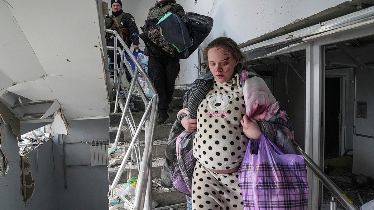 An injured pregnant woman walks downstairs in the damaged by shelling maternity hospital in Mariupol, Ukraine, Wednesday, March 9, 2022.