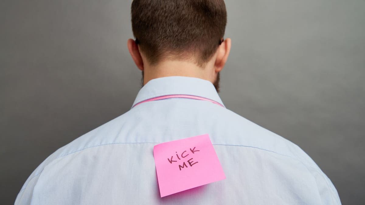 Kick Me prank sign on a man's back