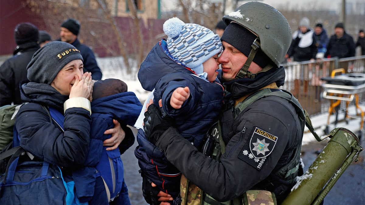 A police officer says goodbye to his son as his family flees from advancing Russian troops as Russia's attack on Ukraine continues in the town of Irpin outside Kyiv, Ukraine, March 8, 2022.
