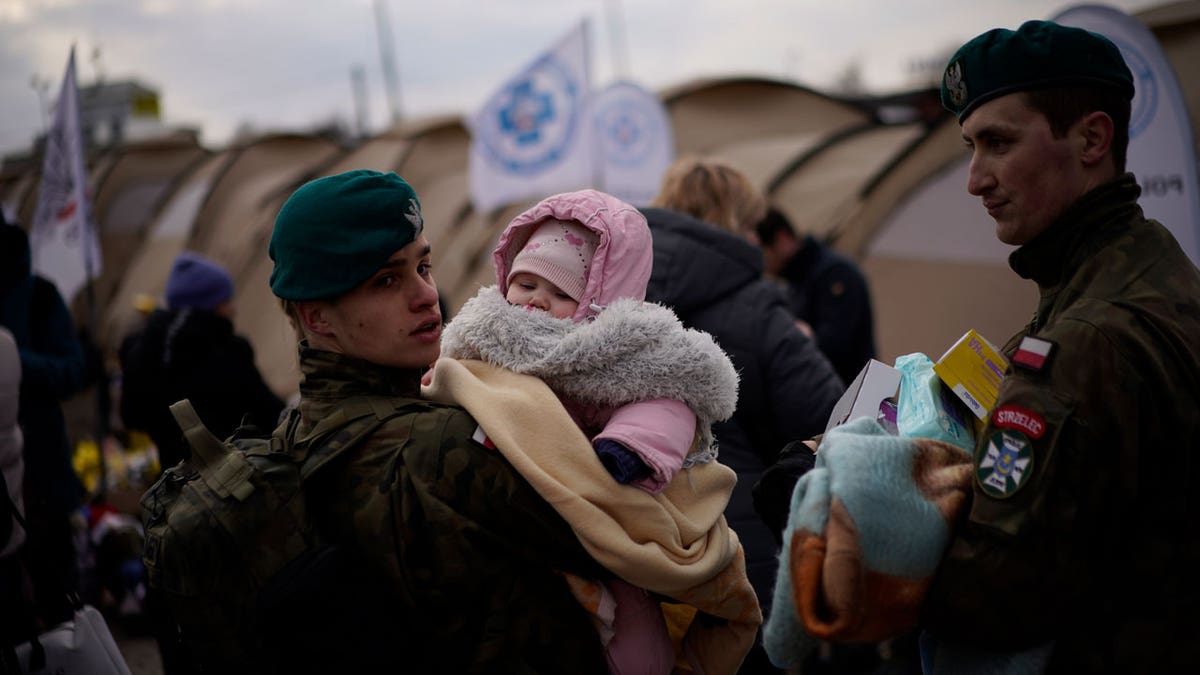 A Polish soldier holds a baby as refugees fleeing war in neighboring Ukraine arrive at the Medyka border, Poland, on Thurs., March 10, 2022. 