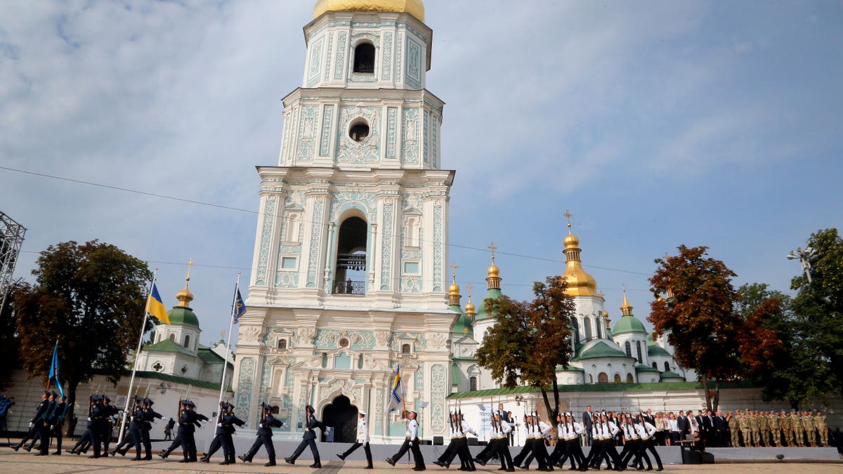 Ukrainian honor guard soldiers march past President Petro Poroshenko, background, in front of St. Sophia Cathedral in Kiev, Ukraine, Tuesday, Aug. 23, 2016, during State Flag Day celebrations.