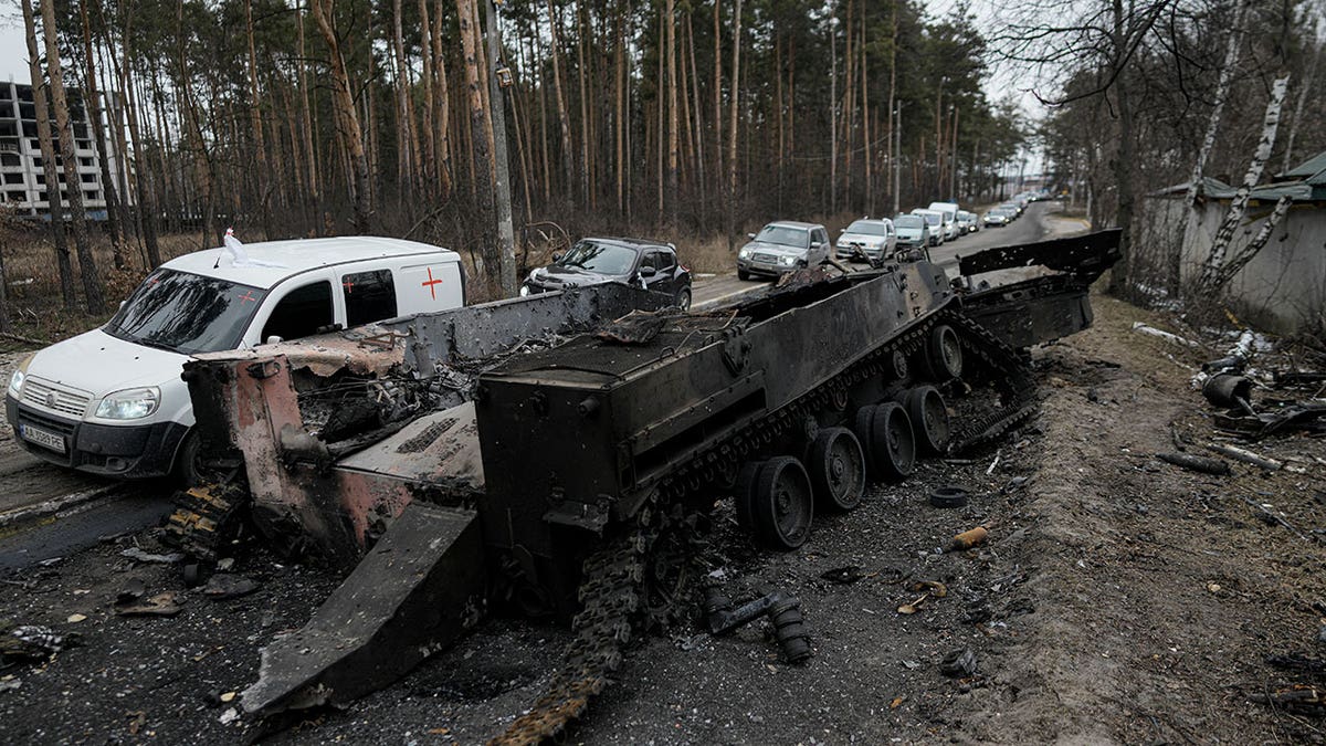 Cars drive past a destroyed Russian tank as a convoy of vehicles evacuating civilians leaves Irpin, on the outskirts of Kyiv, Ukraine, March 9, 2022. 