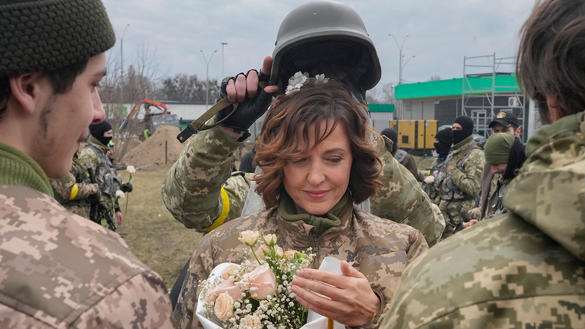 A soldier holds a helmet as a wedding crown during the wedding ceremony for members of the Ukrainian Territorial Defence Forces Lesia Ivashchenko and Valerii Fylymonov, at a checkpoint in Kyiv, Ukraine, Sunday, March 6.