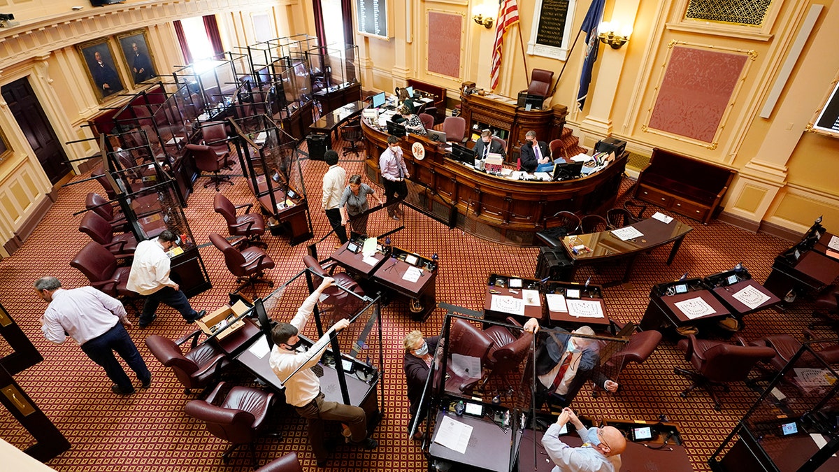 Susan Schaar, center, clerk of the Senate, helps remove COVID barriers after the session at the Capitol on Monday, Feb. 28, 2022, in Richmond, Virginia.