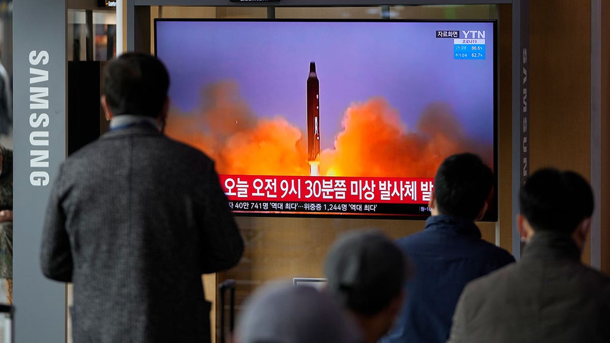 People watch a TV screen showing a news program reporting about North Korea's missile with file footage, at a train station in Seoul, South Korea, Wednesday, March 16, 2022. 