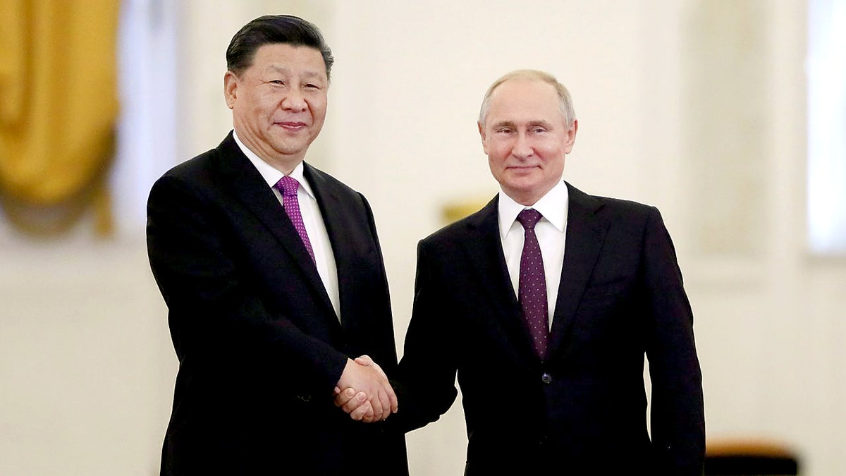 Xi Jinping shakes hands with Vladimir Putin, both men in black suits