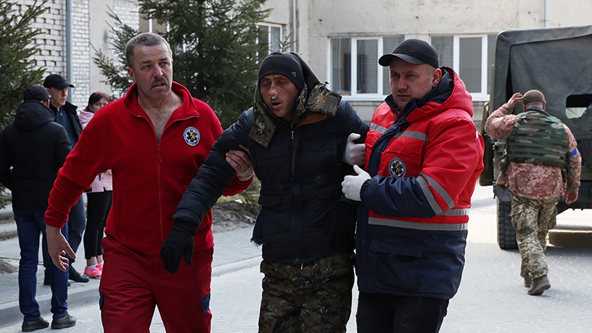 A patient is assisted by medical staff as he arrives at Novoiavorivsk District Hospital on March 13, 2022 in Novoiavorivsk, Ukraine.?