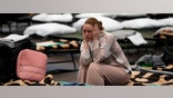 FILE - A woman puts her head in her hands as she sits on a cot in a shelter, set up for displaced persons fleeing Ukraine, inside a school gymnasium in Przemysl, Poland, March 8, 2022. Around 2.5 million people have fled Ukraine in the two weeks since Russia invaded. Most have fled to the European Union. (AP Photo/Markus Schreiber, File)