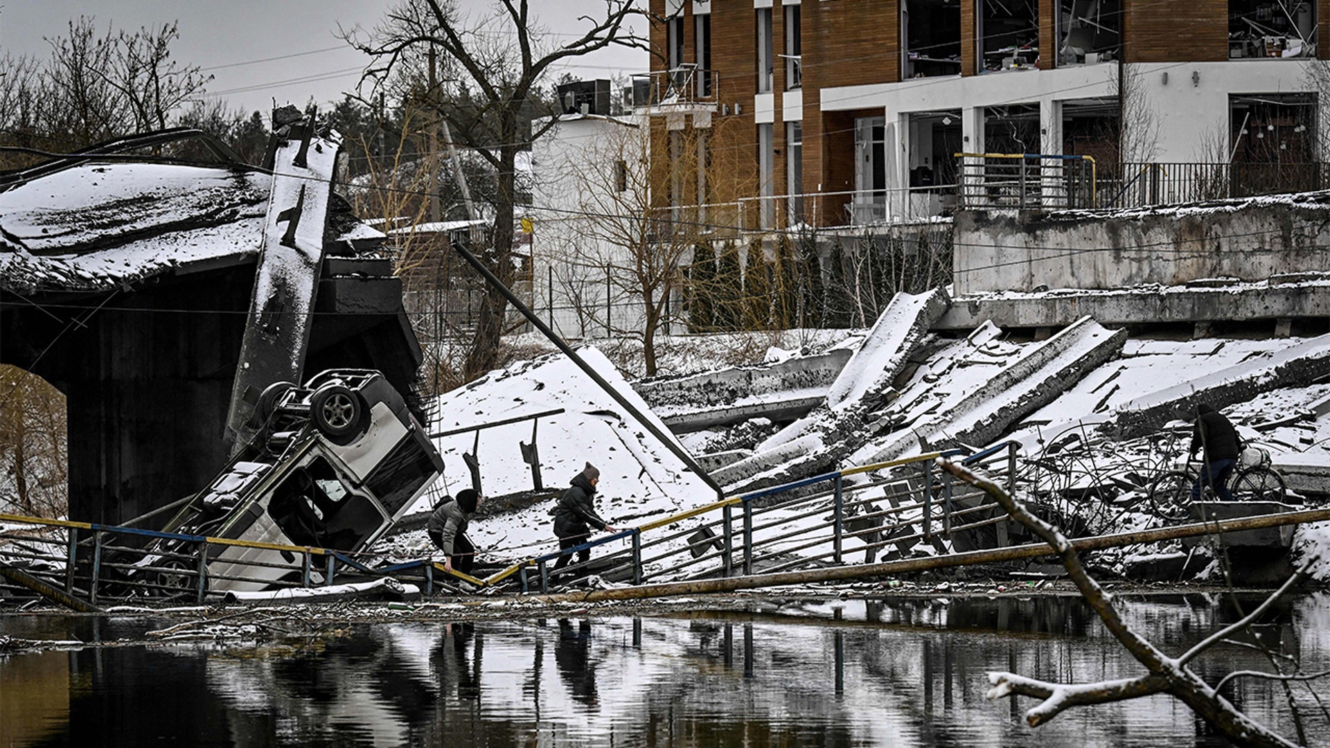 Civilians try to cross a river on a blown up bridge on Kyivs northern front on March 1, 2022.