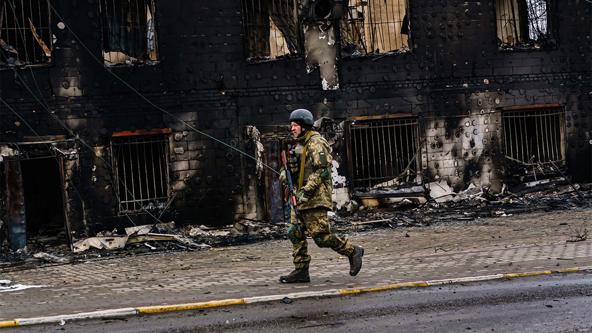 A Ukrainian soldier walks past a building that was destroyed in the midst of battle with the Russians, on the outskirts of Irpin, Ukraine, Tuesday, March 1, 2022.