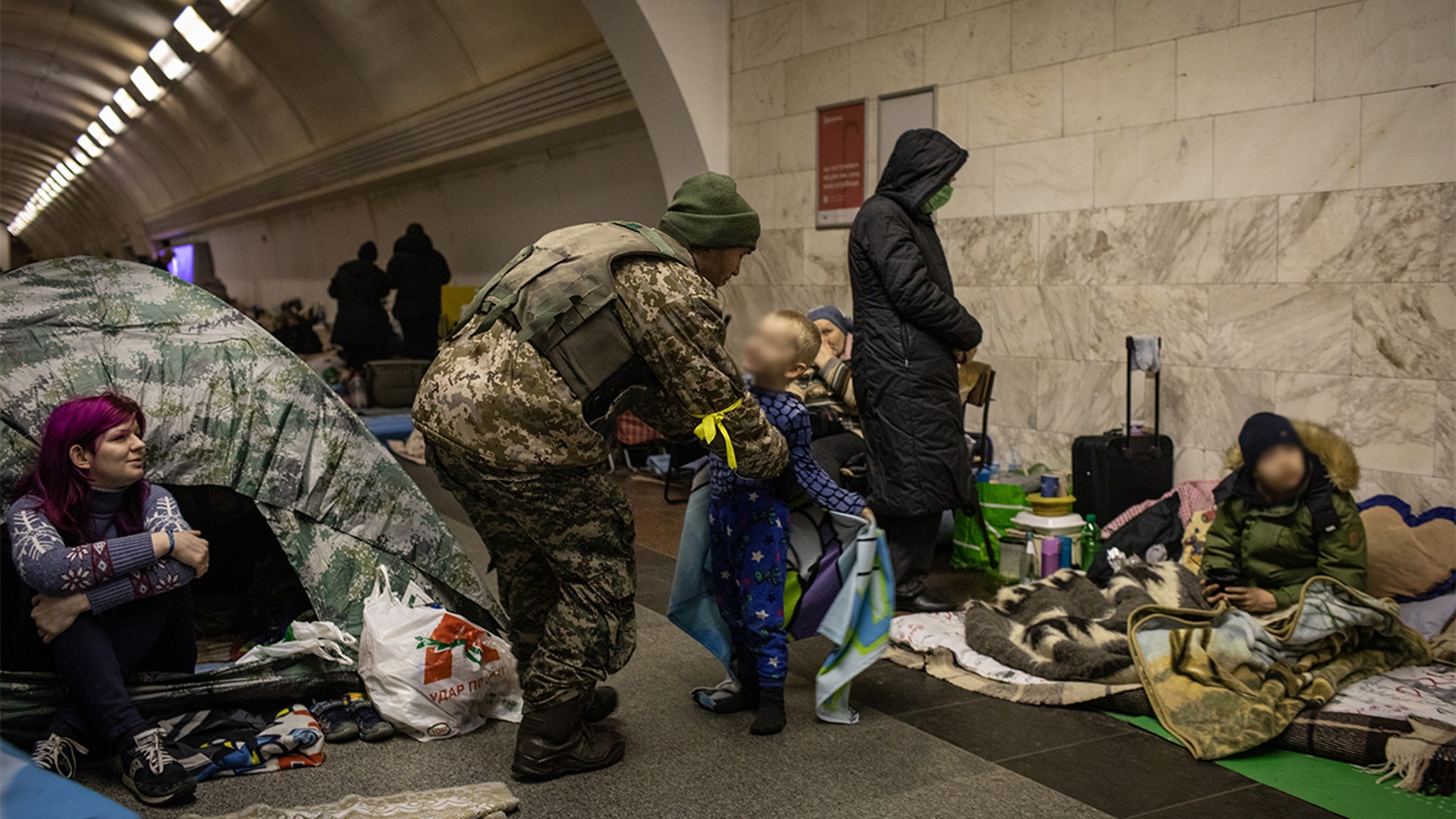 A Ukrainian soldier visits his son who is taking shelter in the lower level of a Kyiv metro station during Russian artillery strikes in Kyiv, Ukraine, on Wednesday, March 2, 2022.