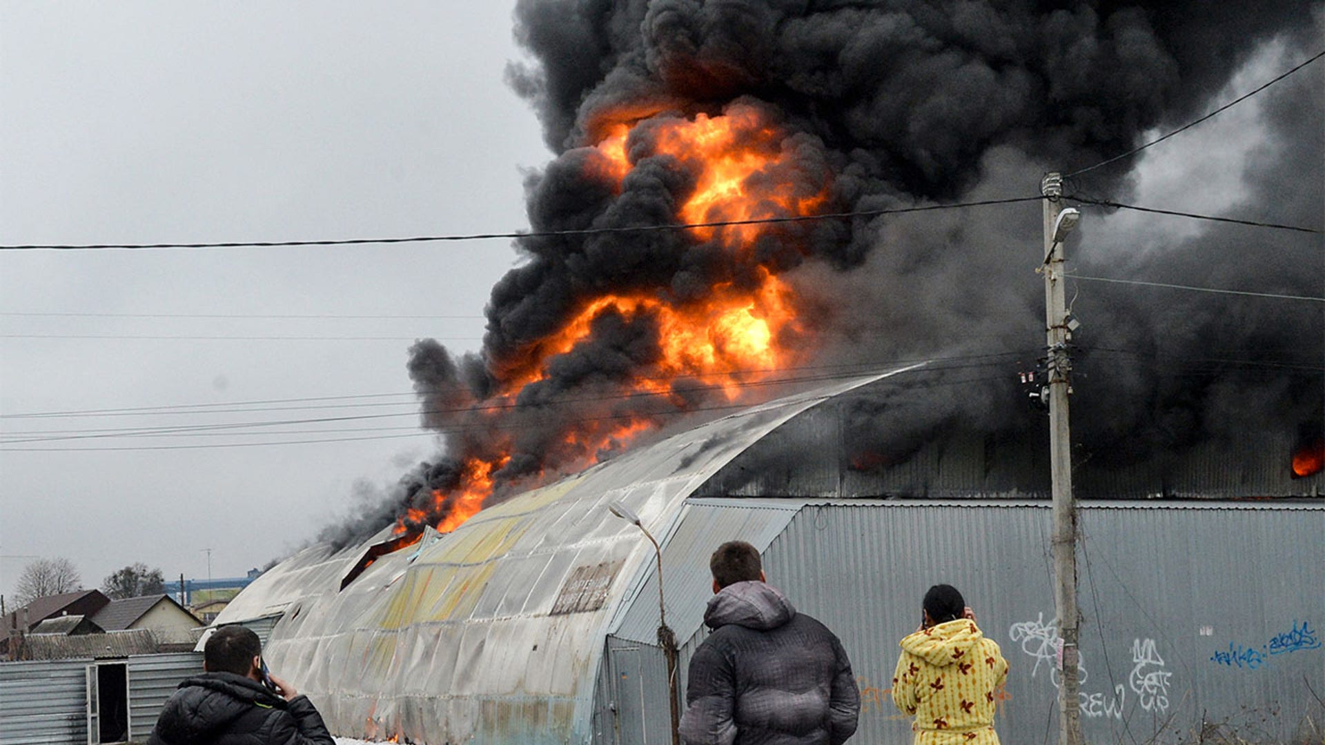 Local residents react in front of burning building after the shelling is said by Russian forces in Ukraine's second-biggest city of Kharkiv on March 3, 2022.