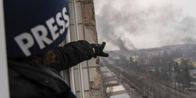 Associated Press photographer Evgeniy Maloletka points at the smoke rising after an airstrike on a maternity hospital, in Mariupol, Ukraine, March 9, 2022.