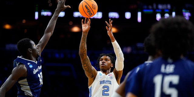 North Carolina's Caleb Love, center goes up for a shot against St. Peter's Fousseyni Drame, left, during the first half of a college basketball game in the Elite 8 round of the NCAA tournament, Sunday, March 27, 2022, in Philadelphia.