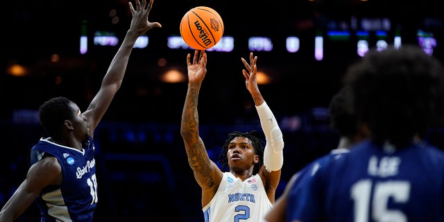 North Carolina's Caleb Love, center goes up for a shot against St. Peter's Fousseyni Drame, left, during the first half of a college basketball game in the Elite 8 round of the NCAA tournament, Sunday, March 27, 2022, in Philadelphia.