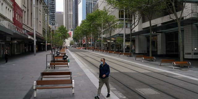 A pedestrian in a protective face mask crosses a quiet street in the city centre during a lockdown to curb the spread of COVID-19 in Sydney, Australia, Sept. 28, 2021. (Reuters/Loren Elliott)